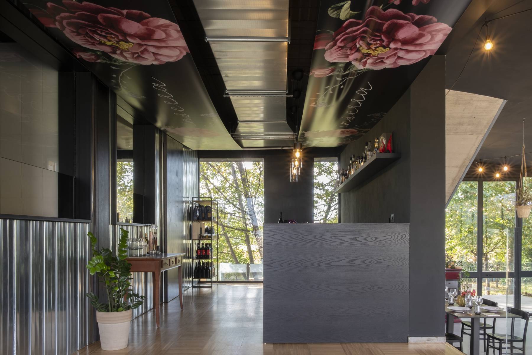 Sala ristorante con soffitto floreale stampato e banco in legno nero
