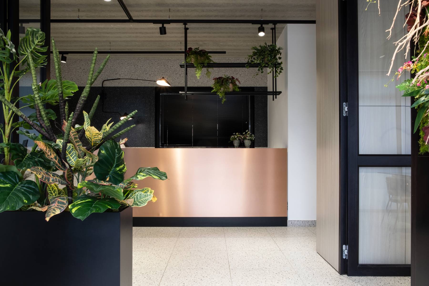 Reception con banco in rame satinato e piante